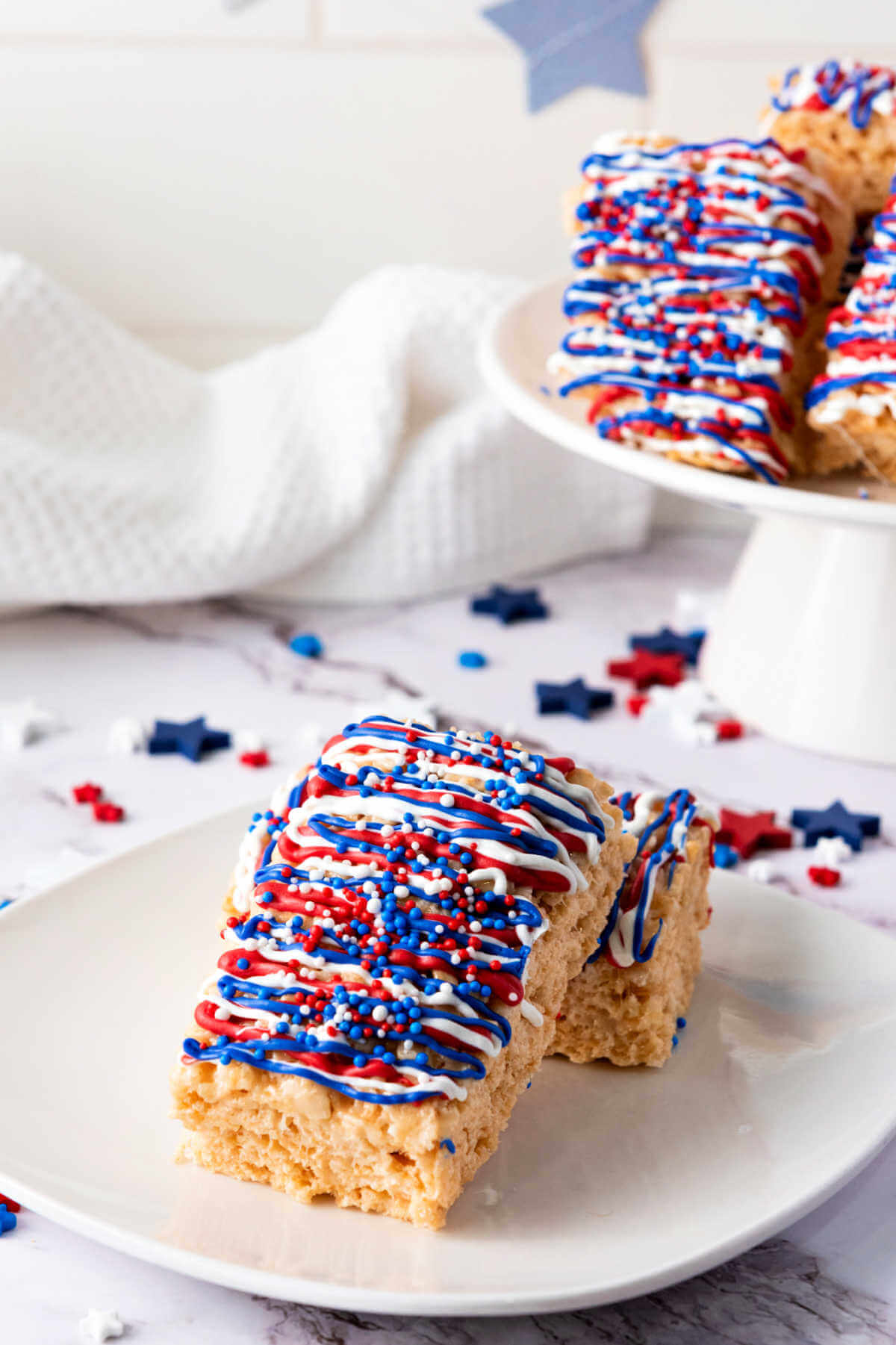 Two patriotic rice Krispy treats leaning on each other on a plate.