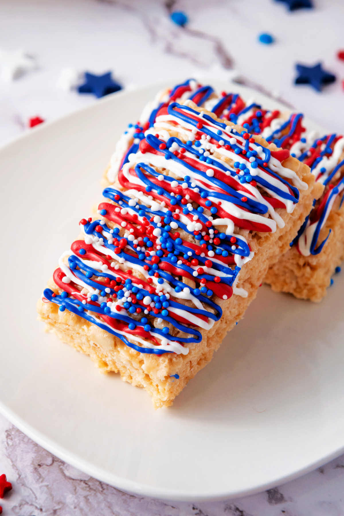 Two red white and blue Krispy treats leaning on each other on a plate.