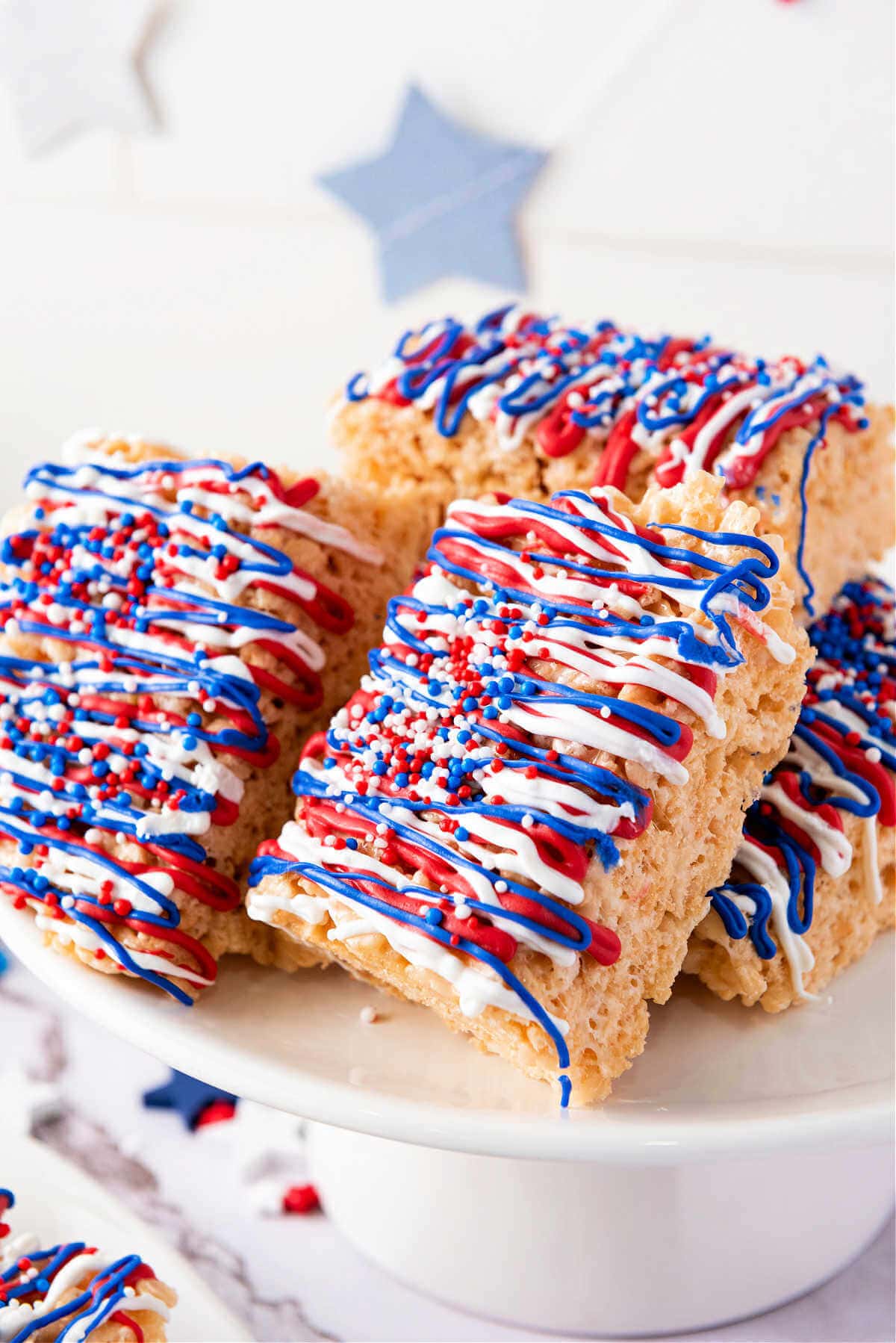Patriotic Krispy treats leaning on each other on a cake stand.
