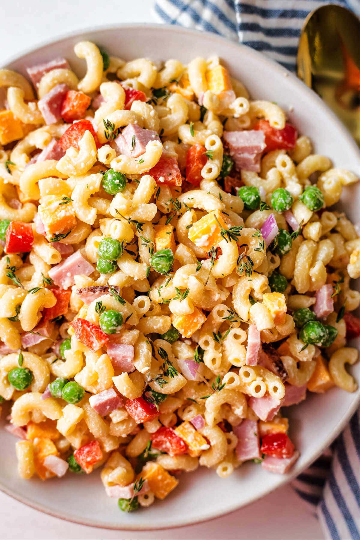 Overhead shot of macaroni salad with peas served in a white serving bowl.