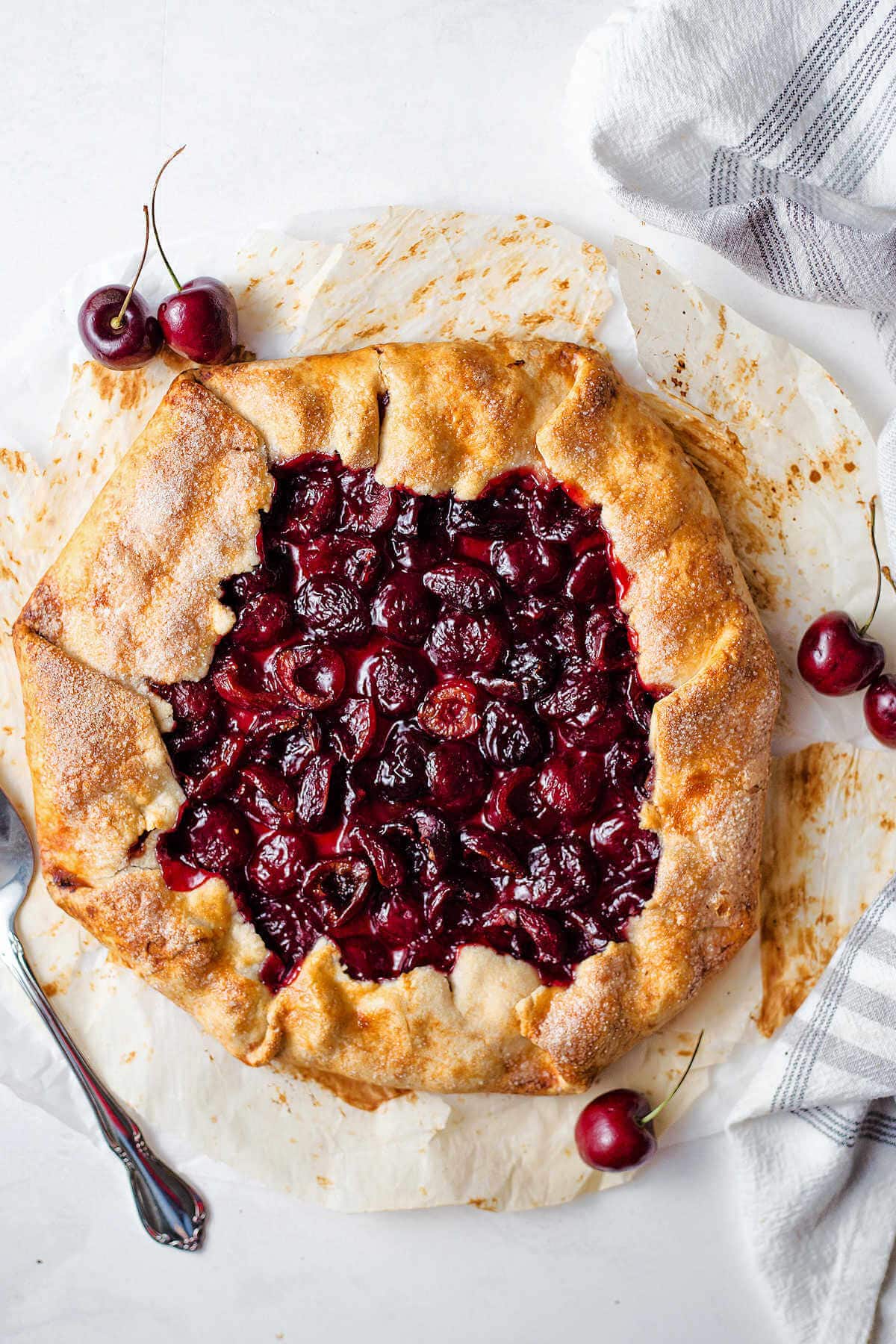 Rustic cherry tart after being baked with fresh cherries around it.