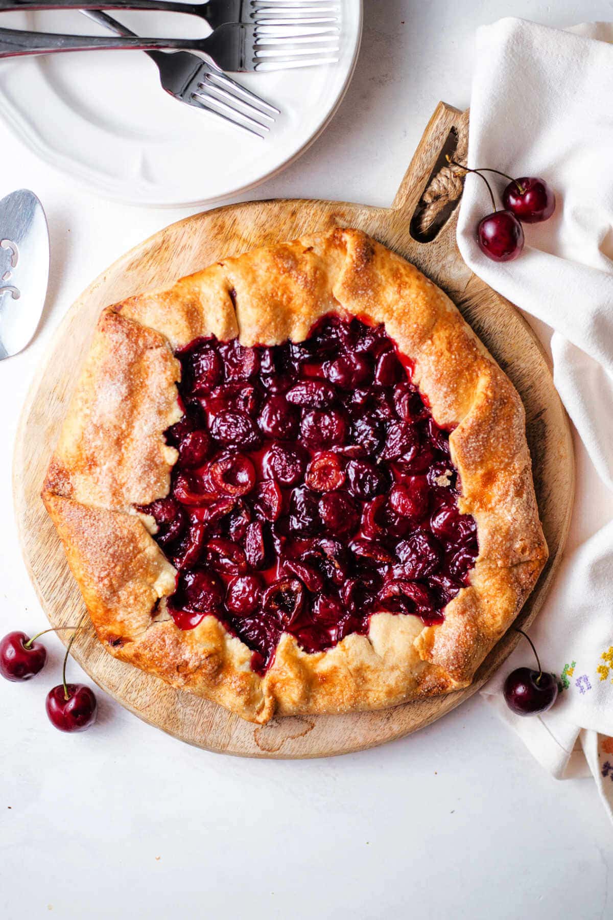 Rustic cherry tart on a round wooden board.