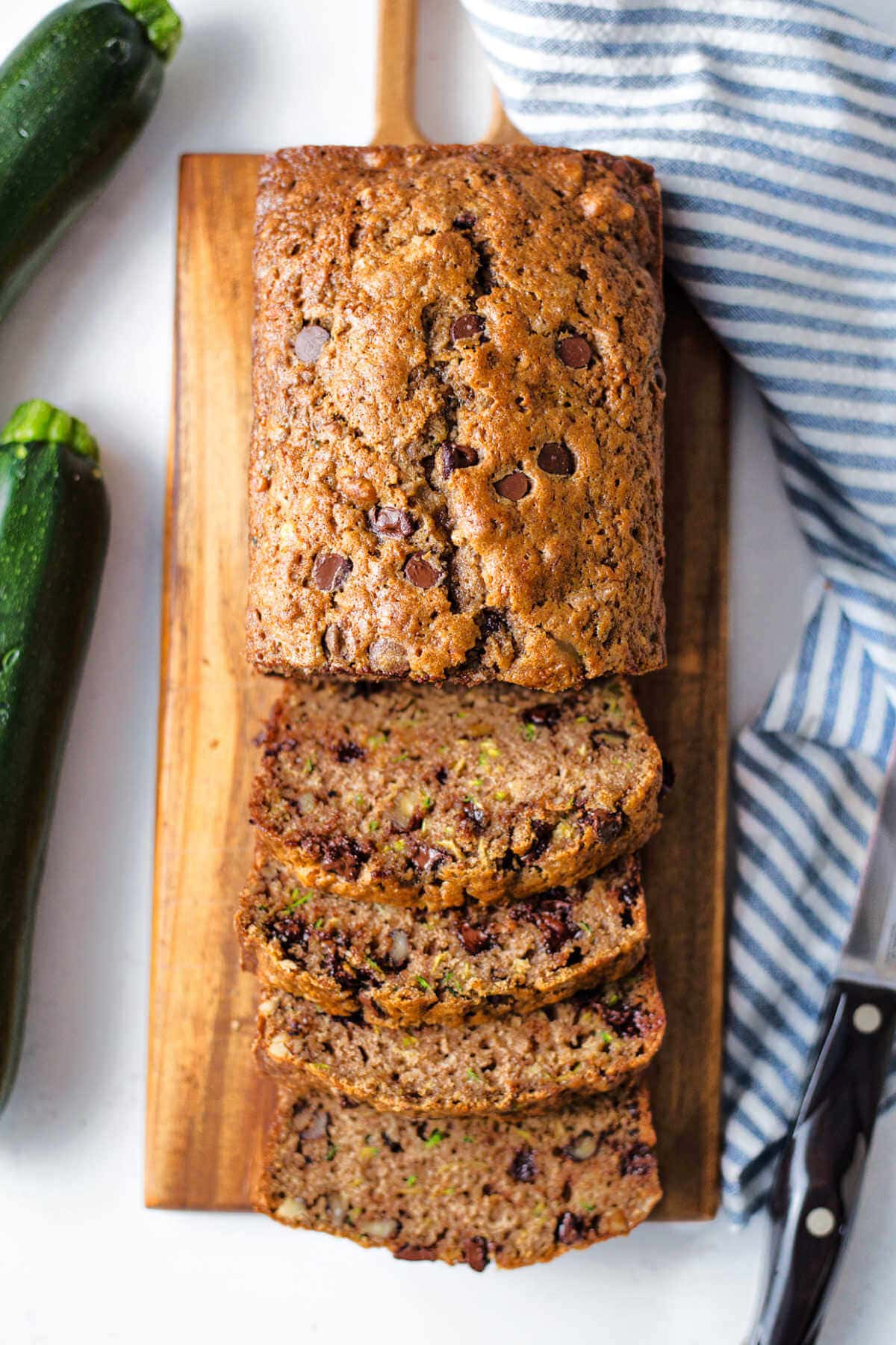 Overhead shot of chocolate chip zucchini bread on a wooden board with some slices off the end.