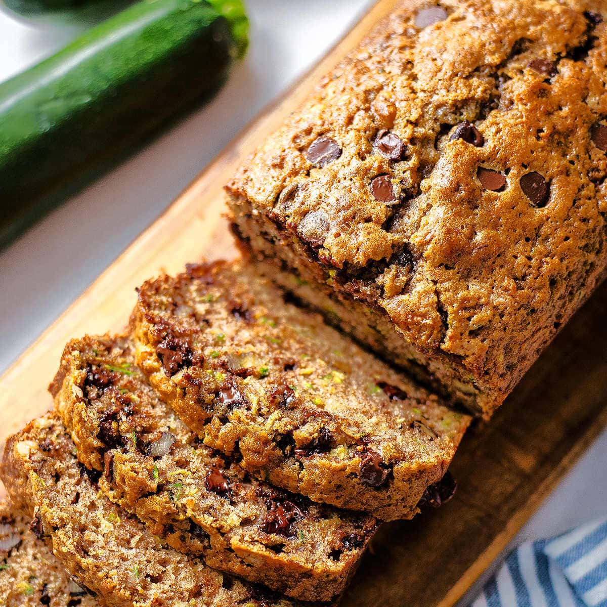 Slices of chocolate chip zucchini bread on a wooden board.