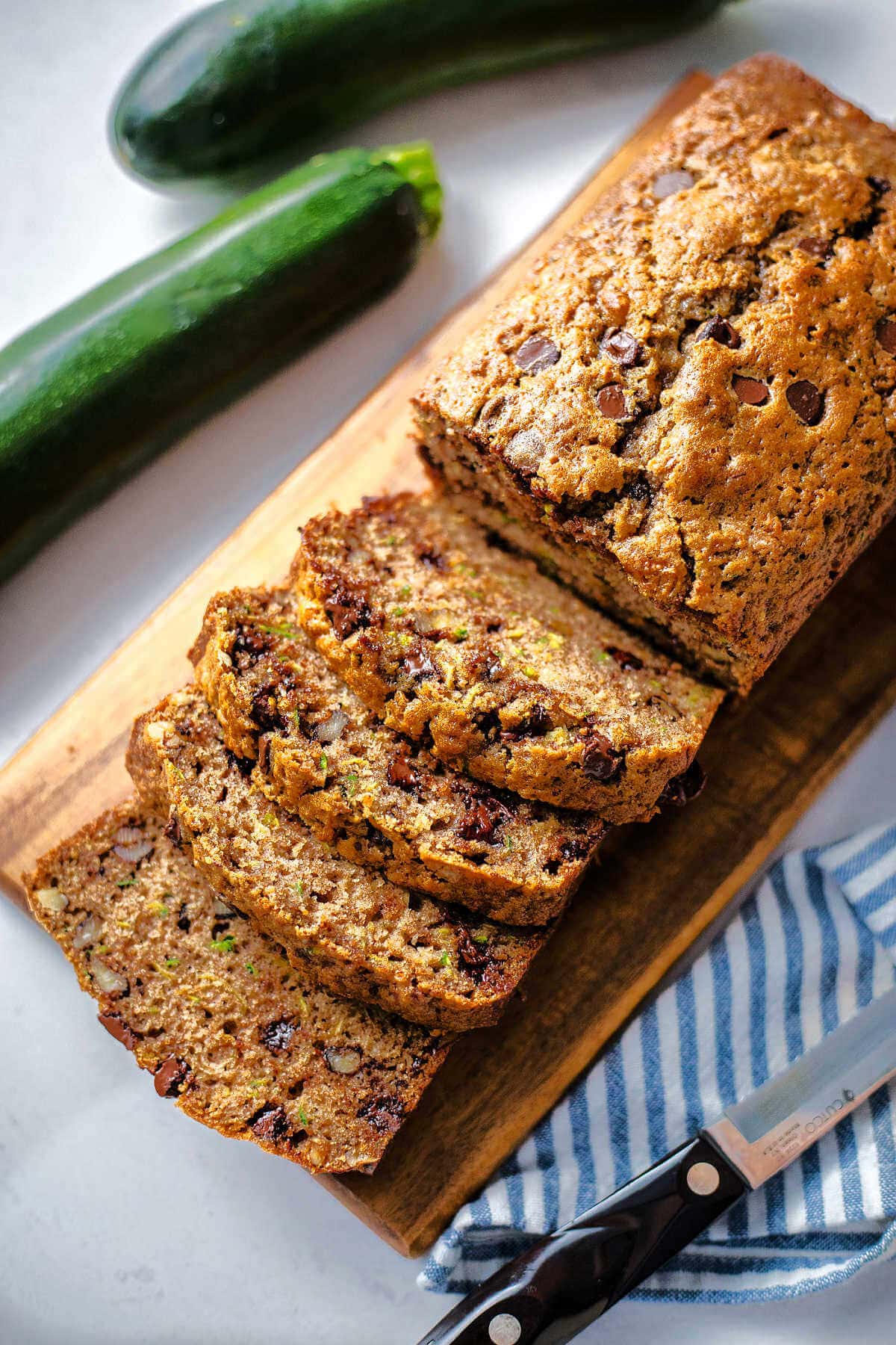 Chocolate chip zucchini bread on a wooden board with some slices off the end.