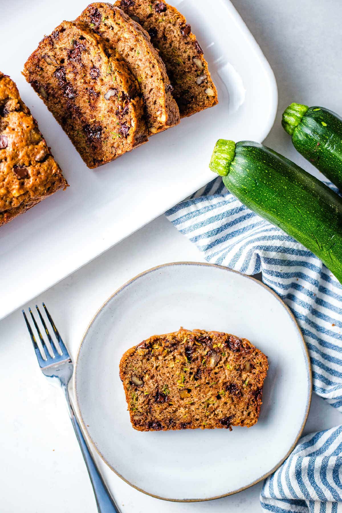 Slice of chocolate chip bread on a plate with some on a serving platter.