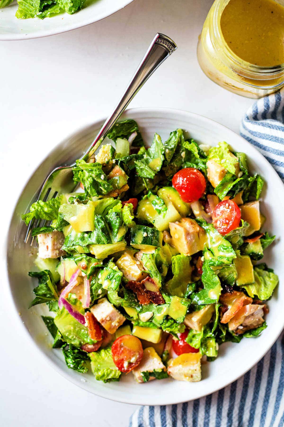 Chopped chicken salad in a bowl with a fork, dressing in the honey mustard dressing.
