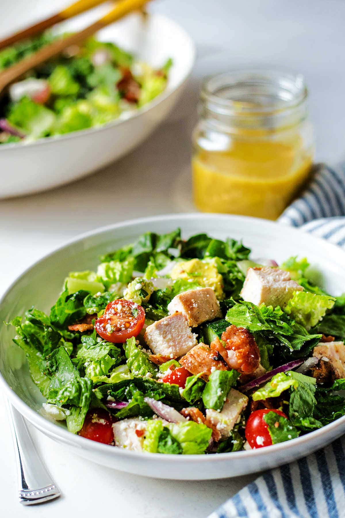 Chopped chicken salad with honey mustard dressing serving in a shallow white bowl.