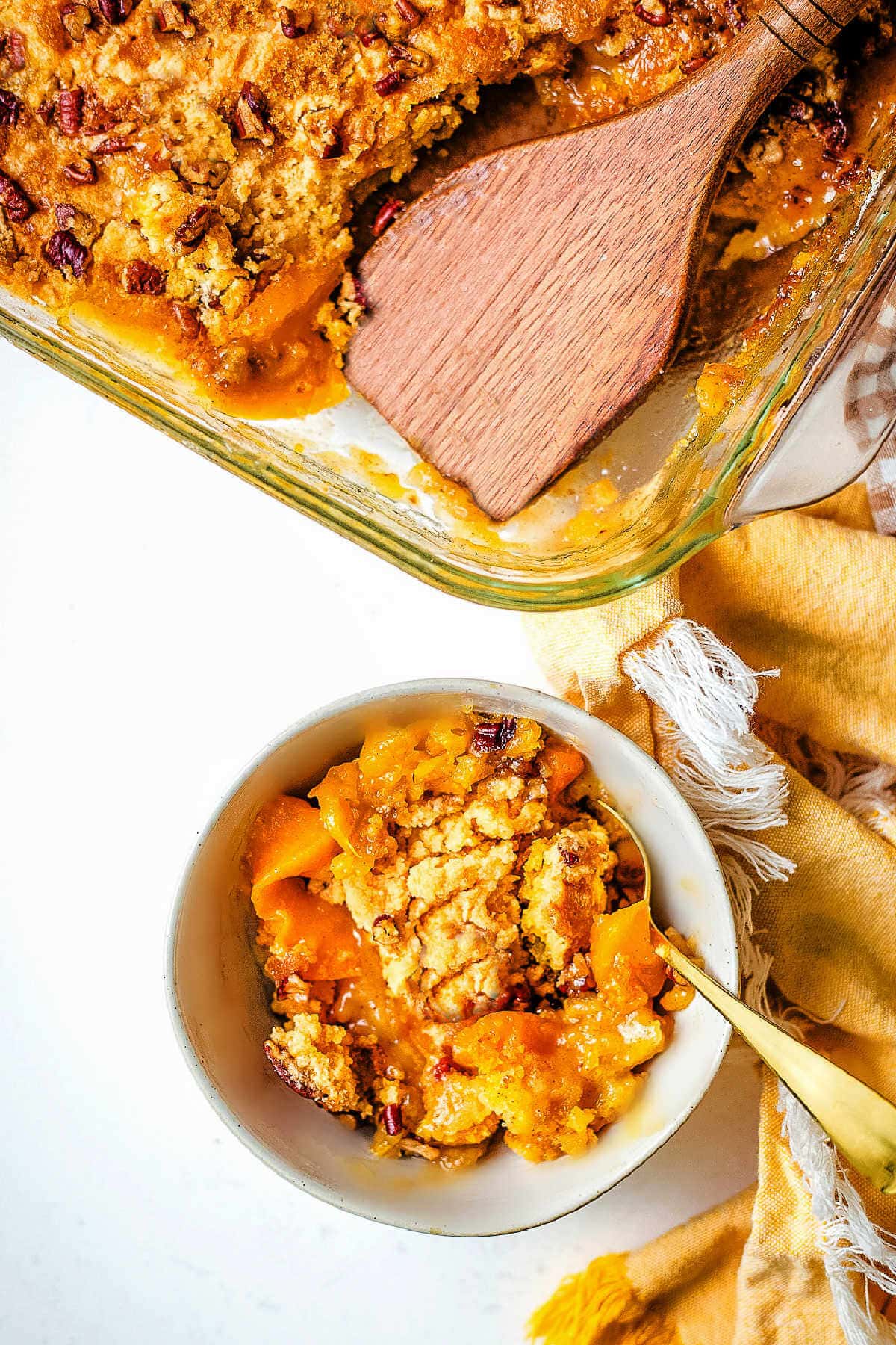 Peach dump cake served in a bowl with the baking dish next to it.