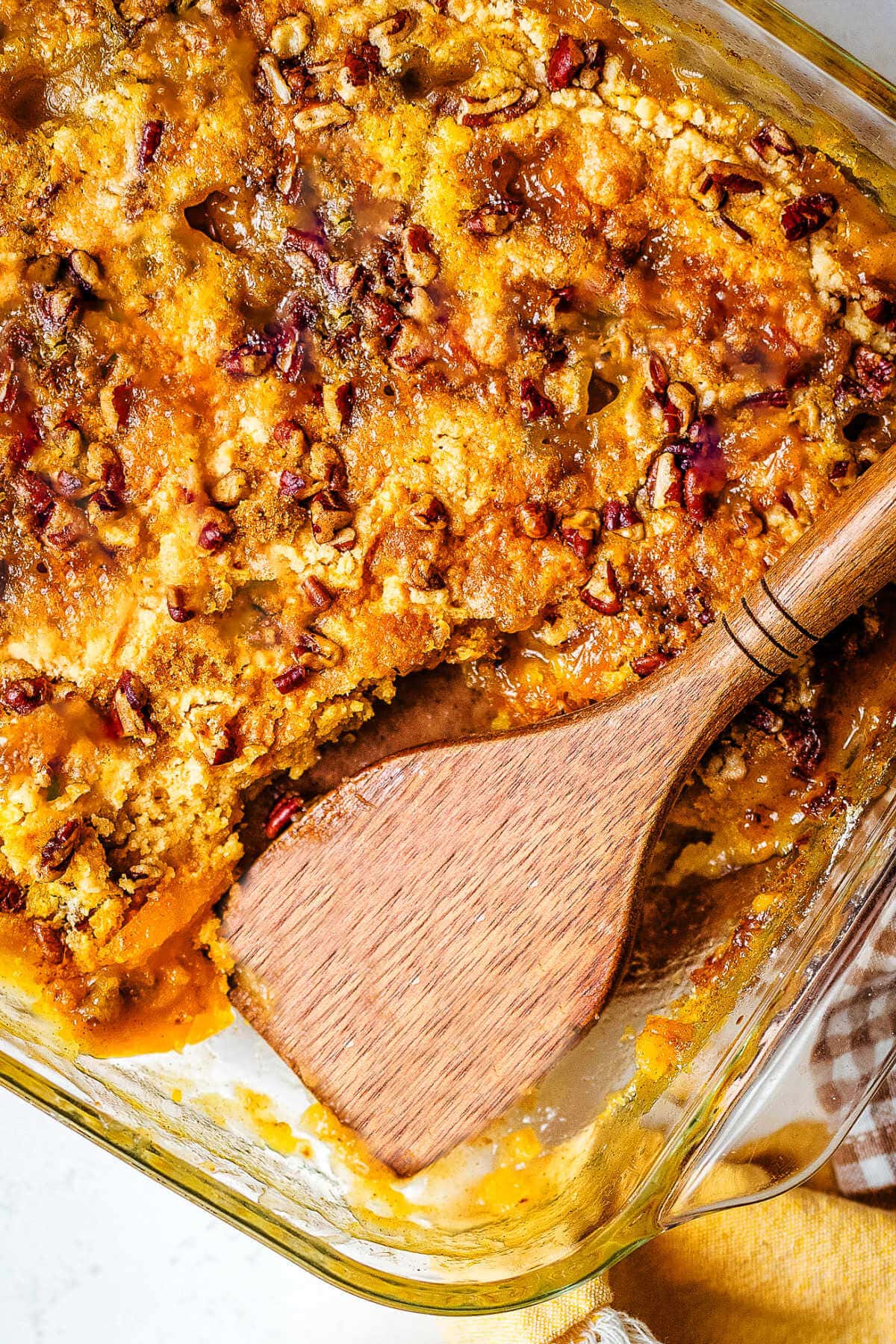 Peach dump cake in a glass baking dish with a portion missing.