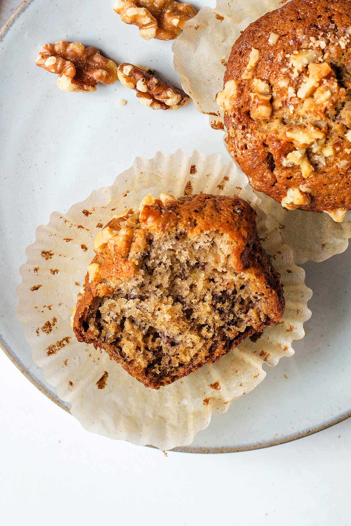Banana nut muffin broken in half to show the inside on a plate.