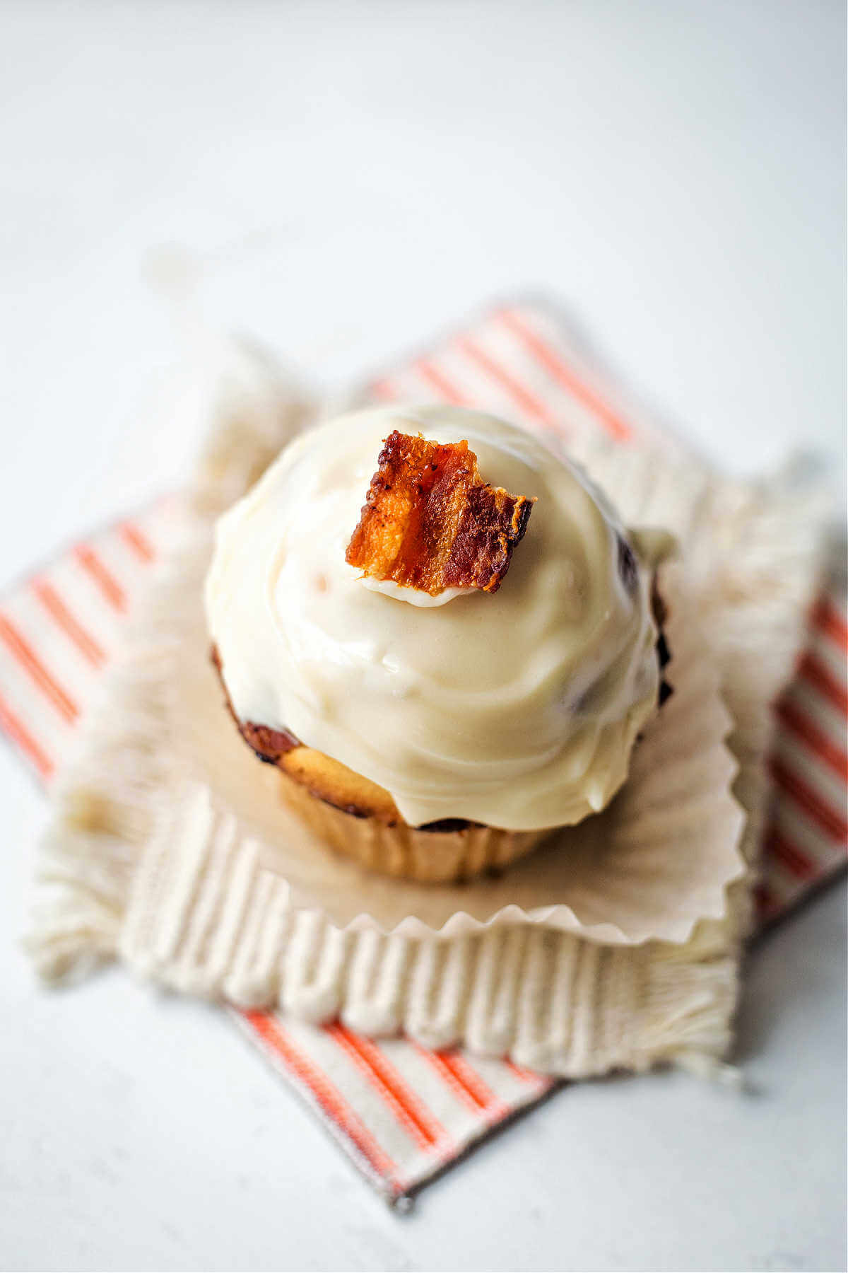 Bacon muffin with maple glaze on a cloth coaster.