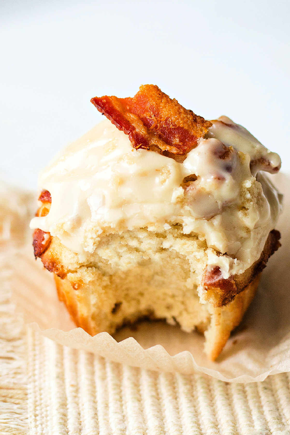Side view of a maple-glazed bacon muffin with a bite out of it.