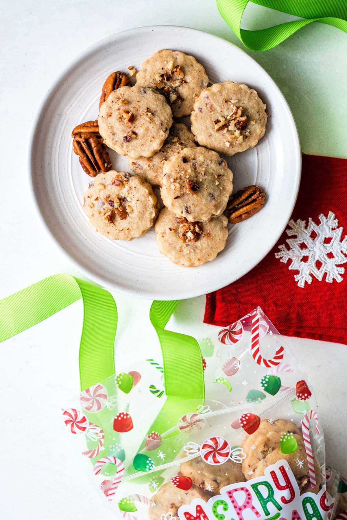 Pecan shortbread cookies on a plate next to a bag of them to gift.