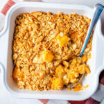 Pineapple cheese casserole in a baking dish with a spoon.