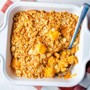 Pineapple cheese casserole in a baking dish with a spoon.