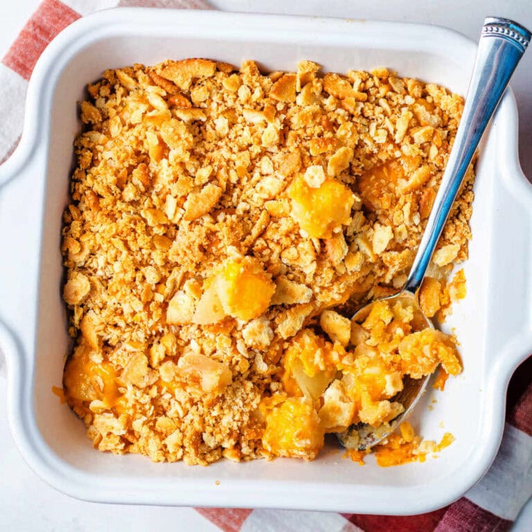 Pineapple cheese casserole in a baking dish with a spoon.