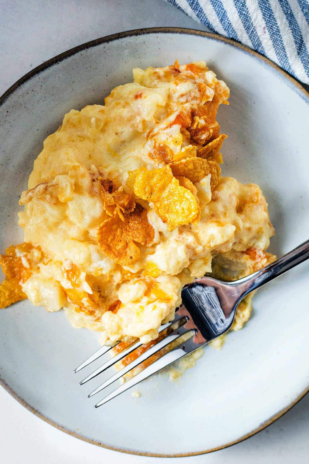 Serving of cheesy funeral potatoes in a bowl with a fork.