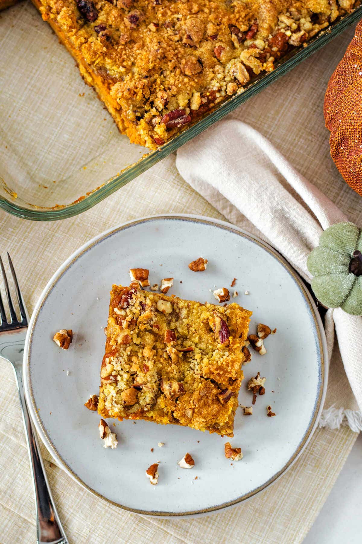 Slice of pumpkin dump cake on a plate topped with extra pecans.