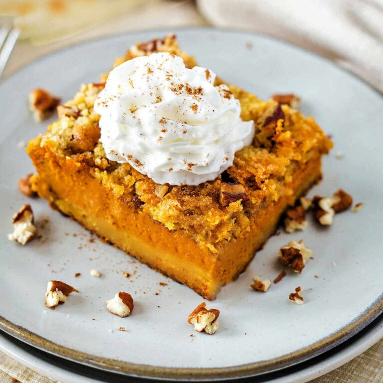 A slice of Pumpkin Dump Cake garnished with whipped topping and pecans.