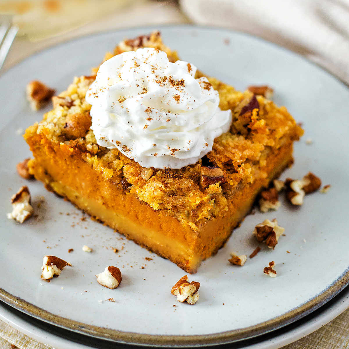 A slice of Pumpkin Dump Cake garnished with whipped topping and pecans.
