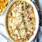 Cheesy sausage dip with beans and spinach in a baking dish.