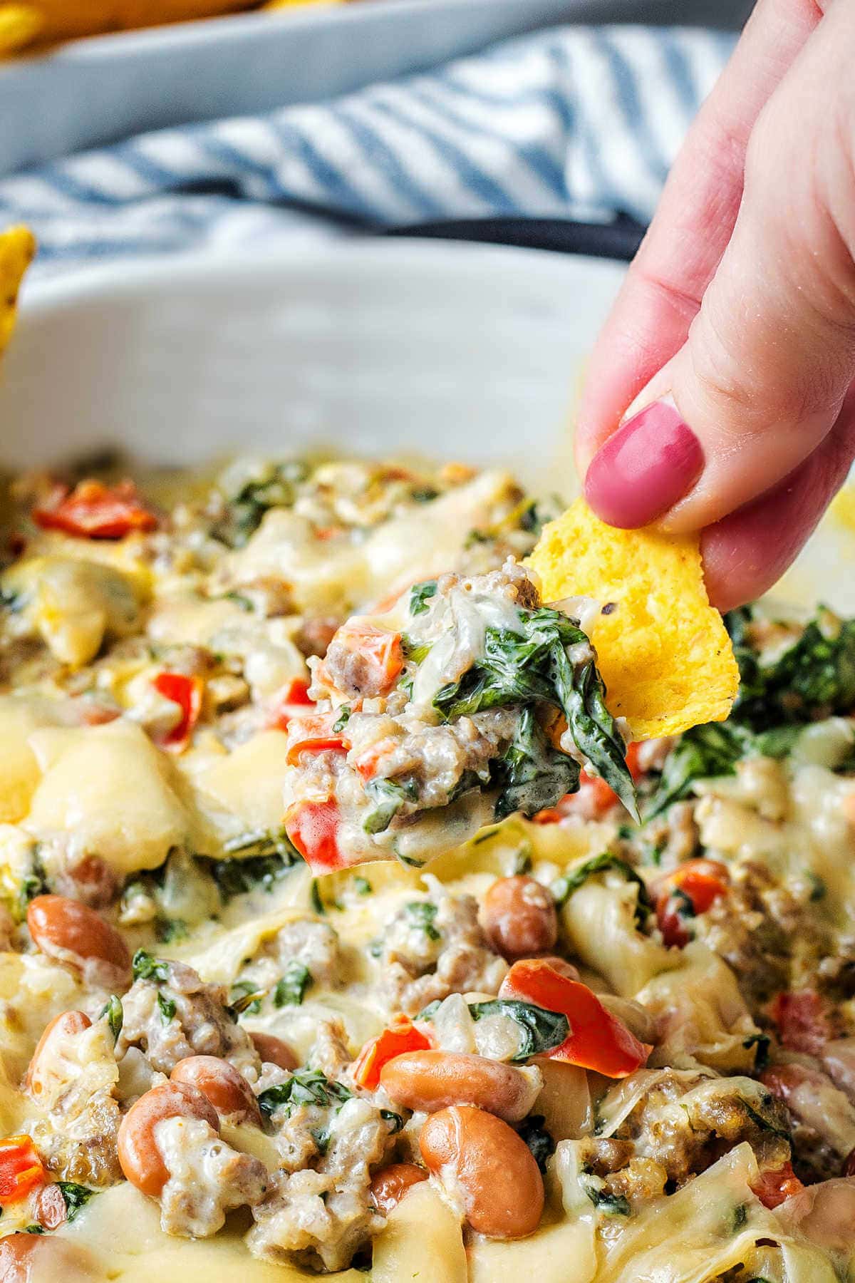 Hand dipping a chip into the sausage dip.