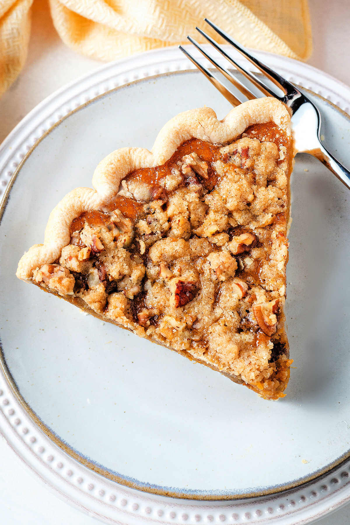 Slice of sweet potato pie on a white plate with a crumble topping.