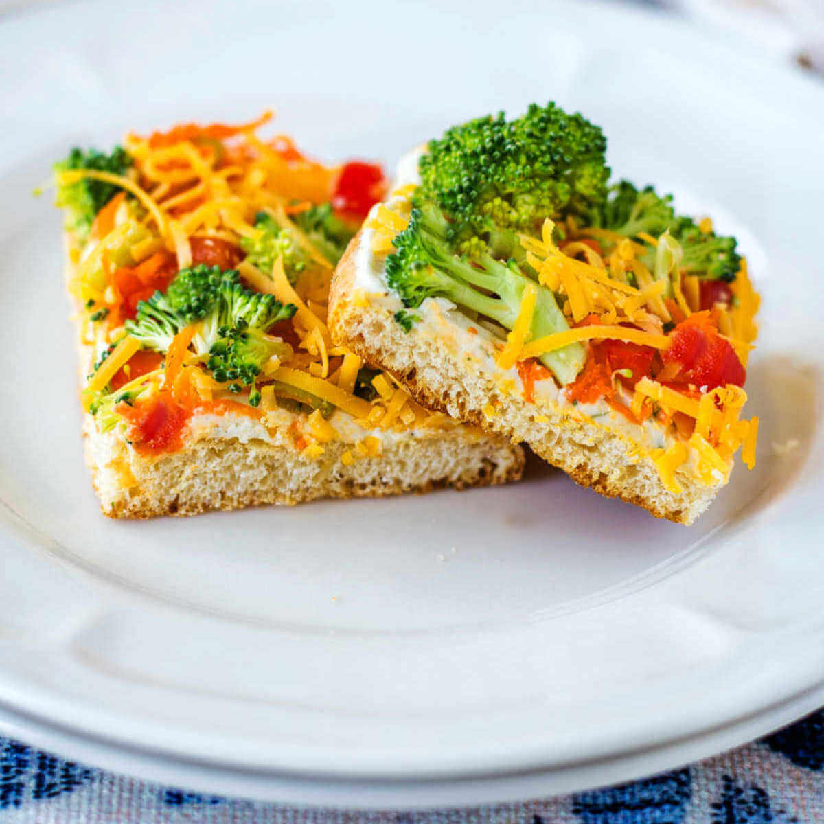 Two square pieces of Cold Veggie Pizza Appetizers on a plate.