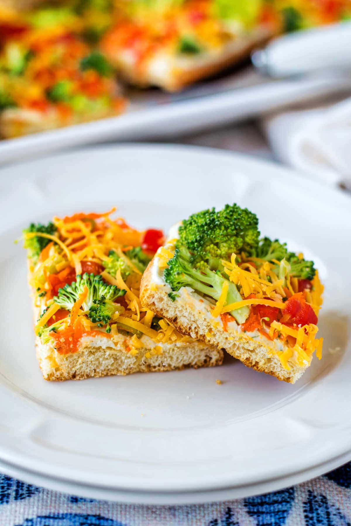 Two slices of crescent roll veggie pizza on a plate leaning on each other.
