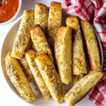Cheesy Garlic Breadsticks on a plate with a bowl of marinara to the side.