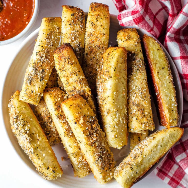 Cheesy Garlic Breadsticks on a plate with a bowl of marinara to the side.