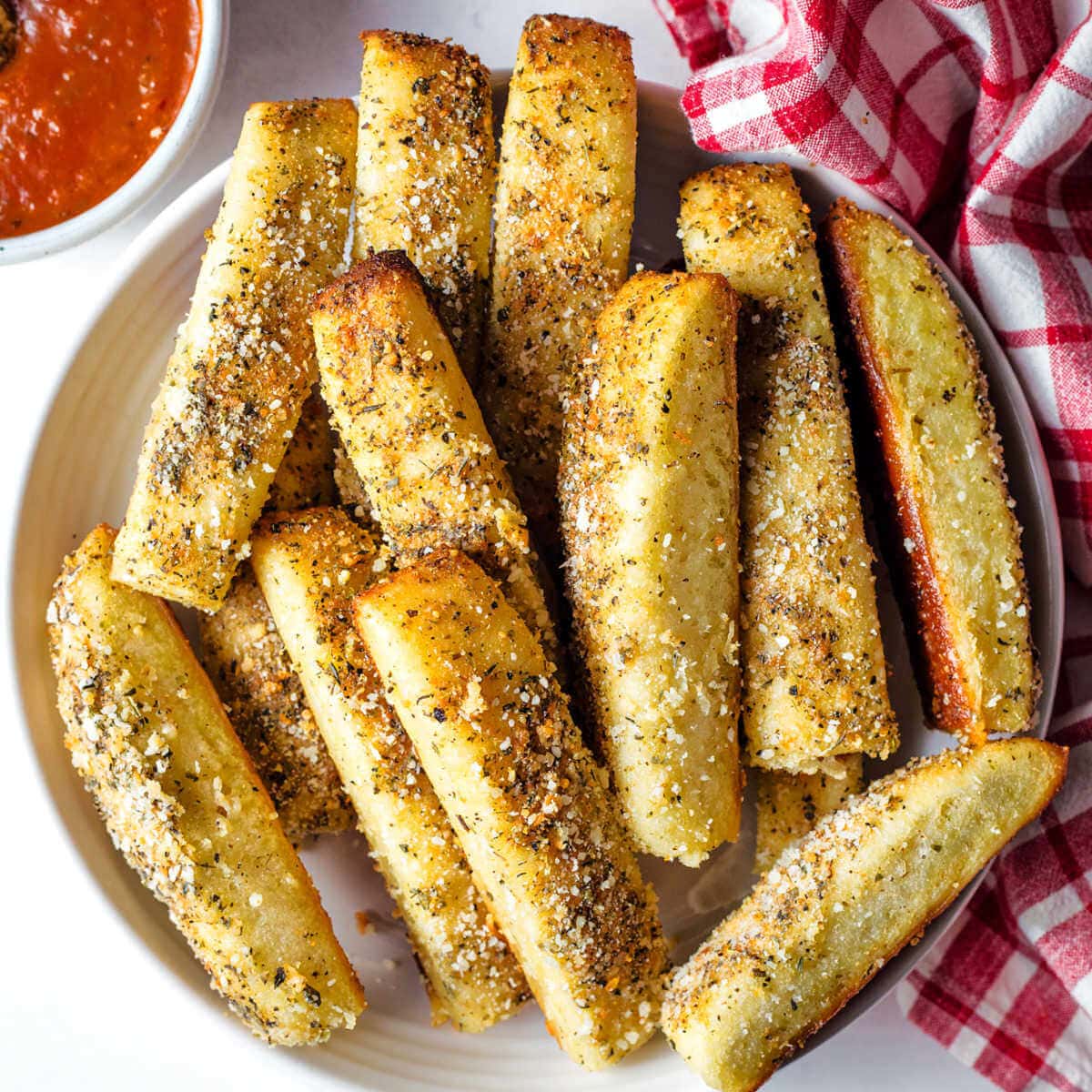 Cheesy Garlic Breadsticks on a plate with a bowl of marinara to the side.