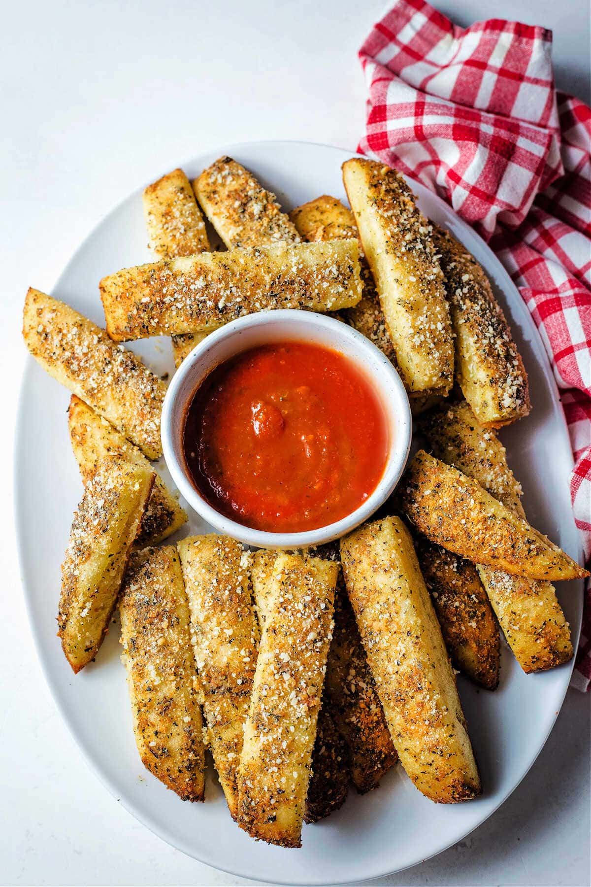 Pizza dough breadsticks served on a serving platter with marinara sauce.