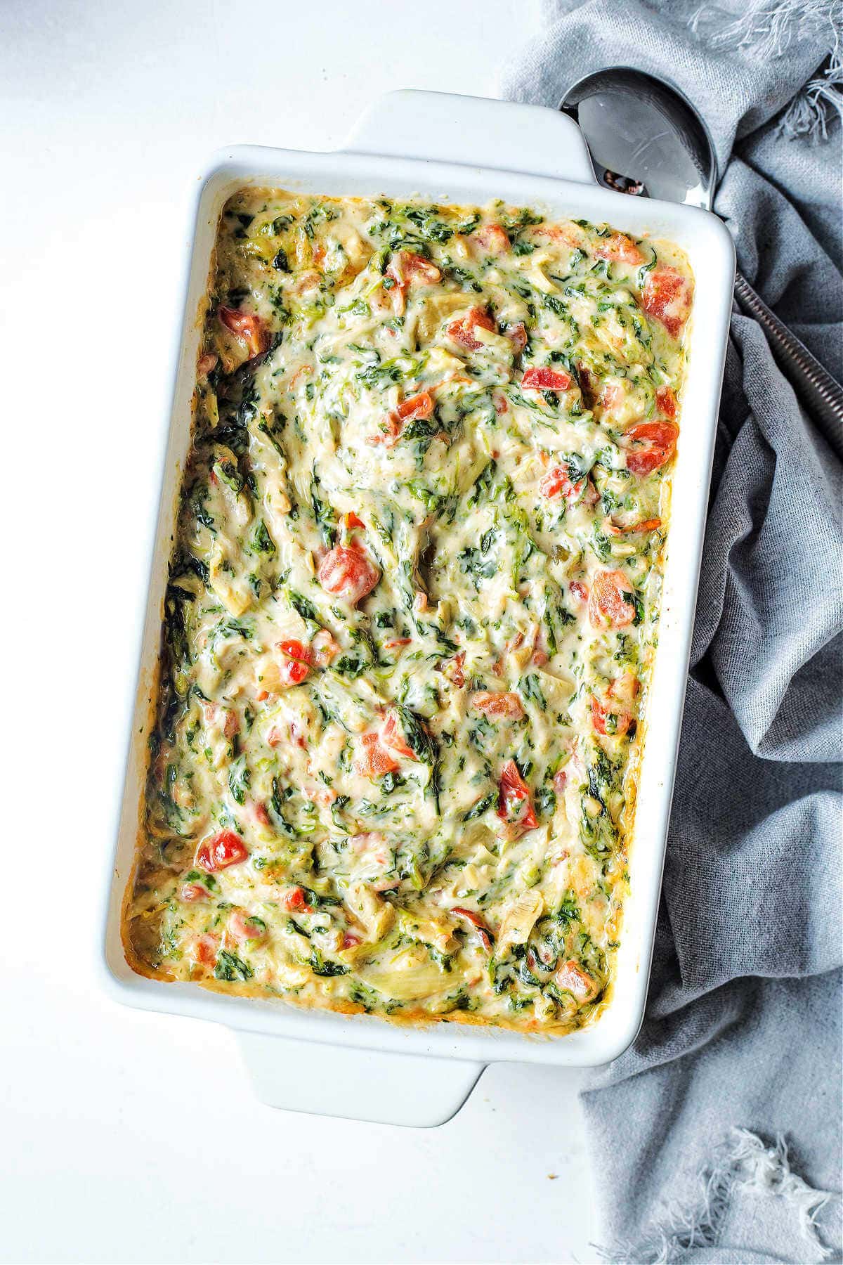 Overhead shot of baked easy spinach artichoke dip in a white baking dish.