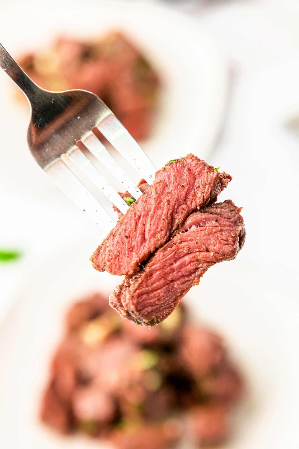 Fork with two steak bites on it.