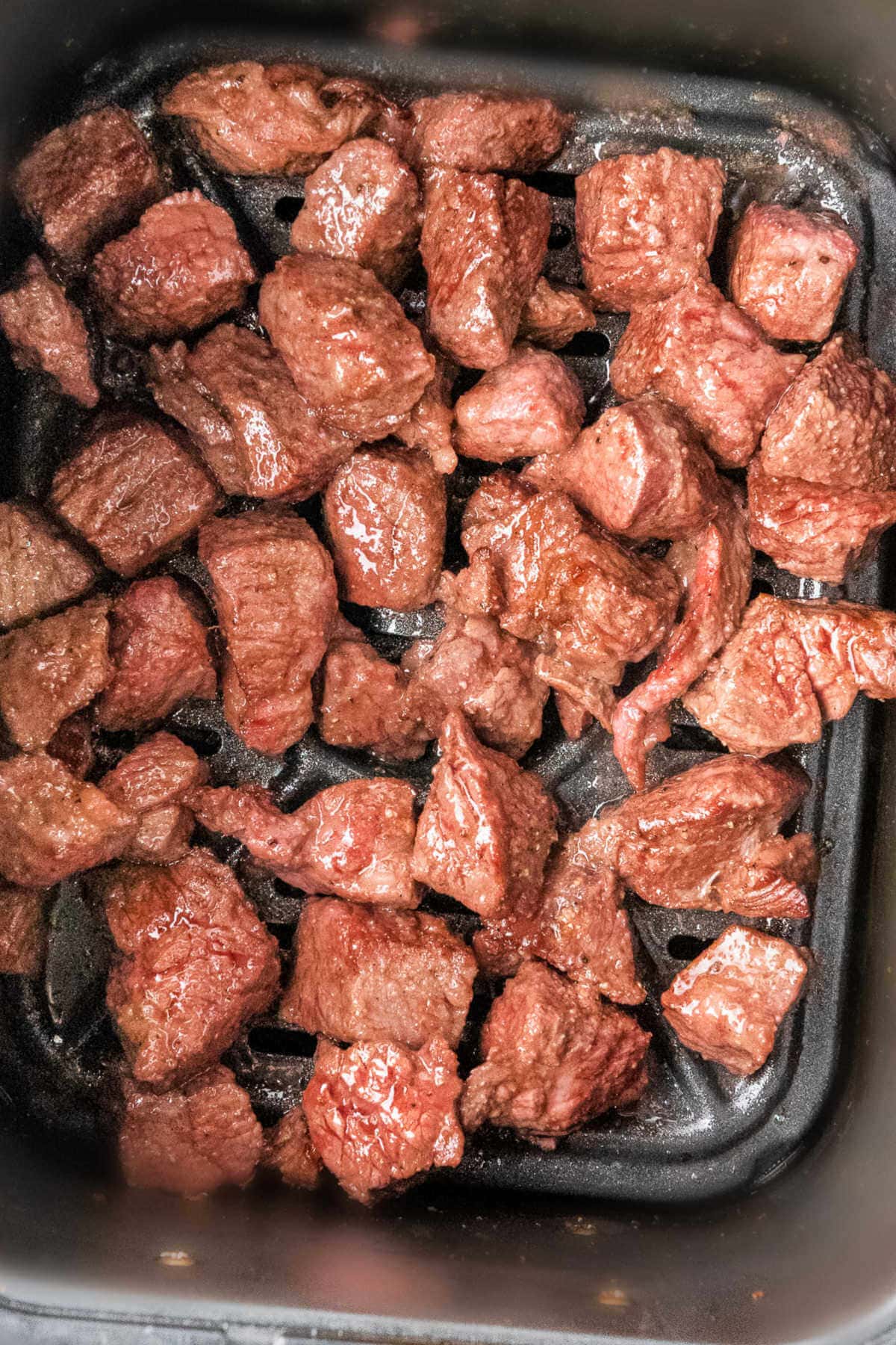 Steak bites in the basket of an air fryer.