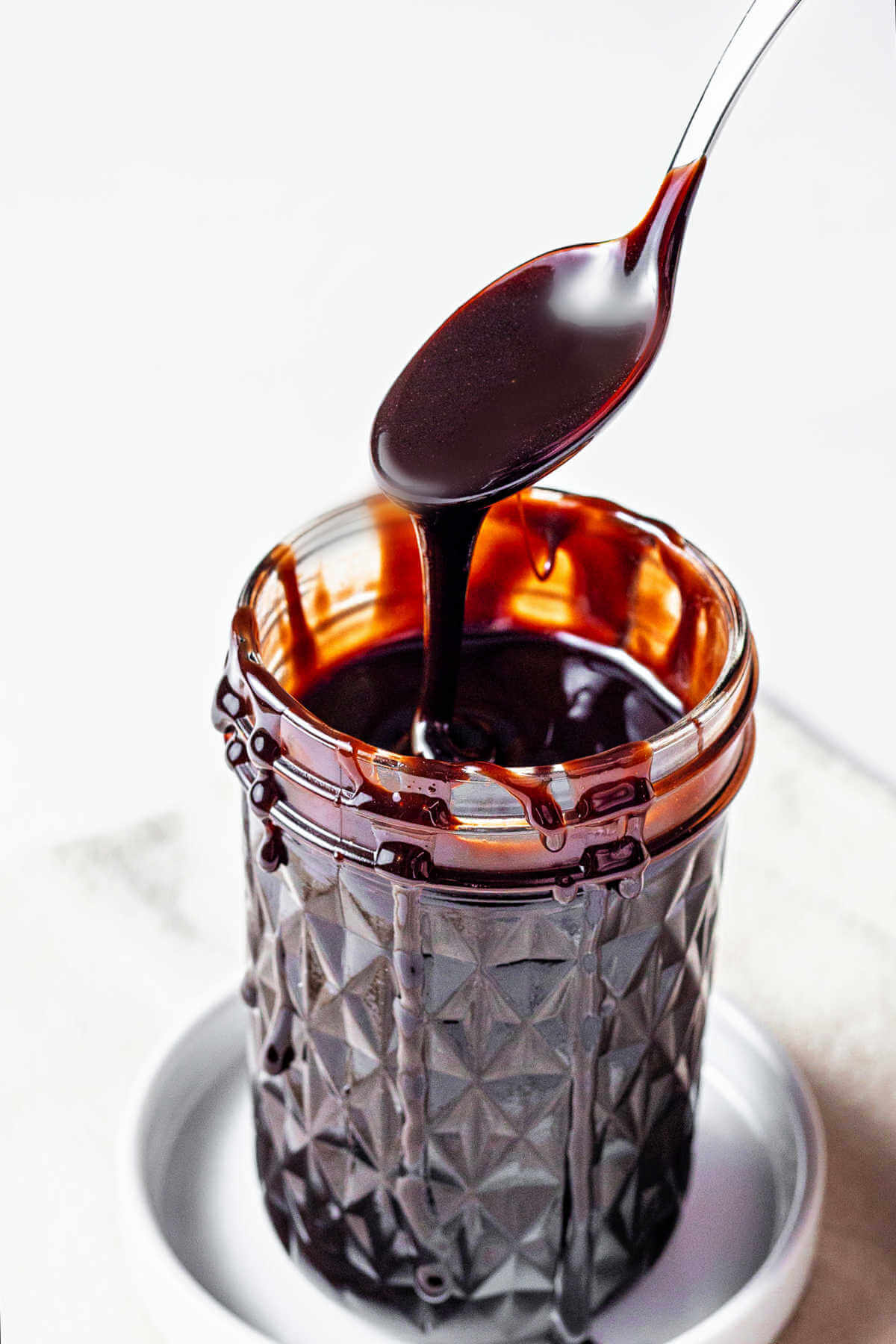 Chocolate sauce in a jar with a spoon scooping some up.