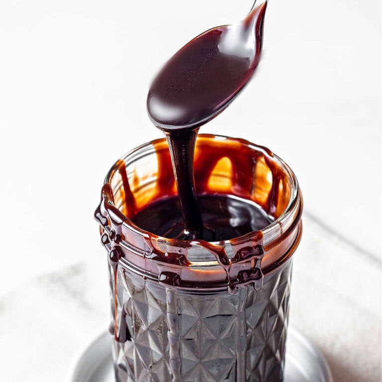 Chocolate sauce in a jar with a spoon scooping some up.