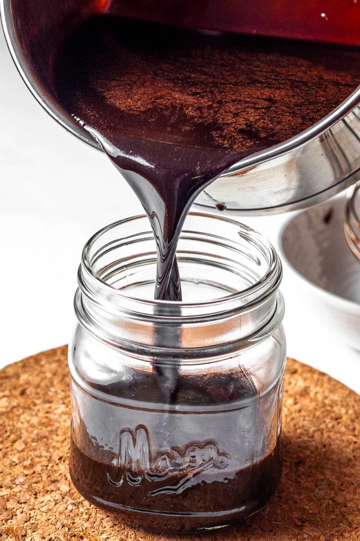 Pouring the chocolate sauce into a small jar from the saucepan.