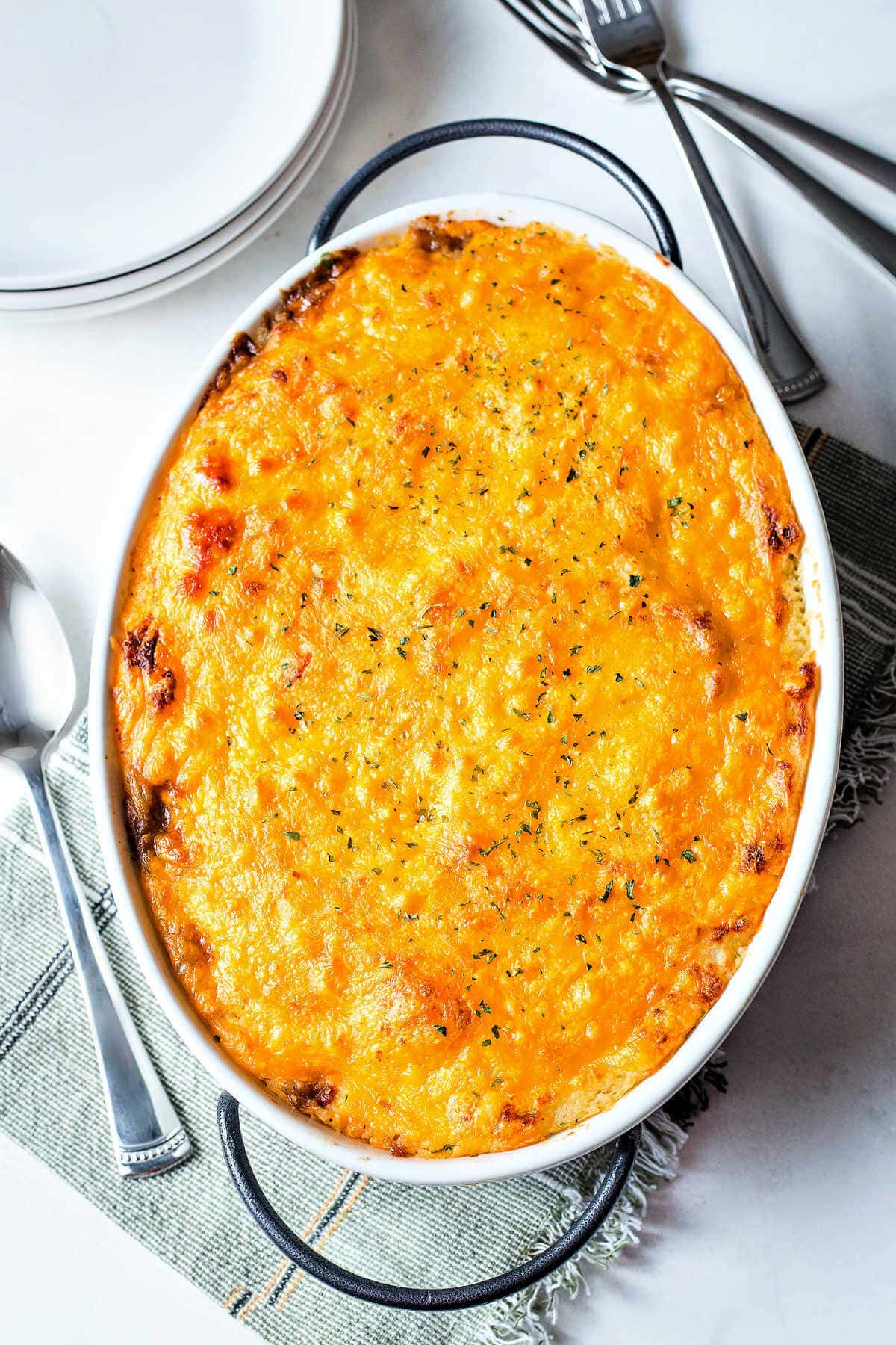 Baked shepherd's pie in a white baking dish with a cheesy layer on top.