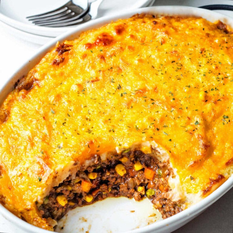 Shepherd's Pie in a baking dish with a serving missing so that you see the layers of the meat filling and the cheesy mashed potatoes on top.