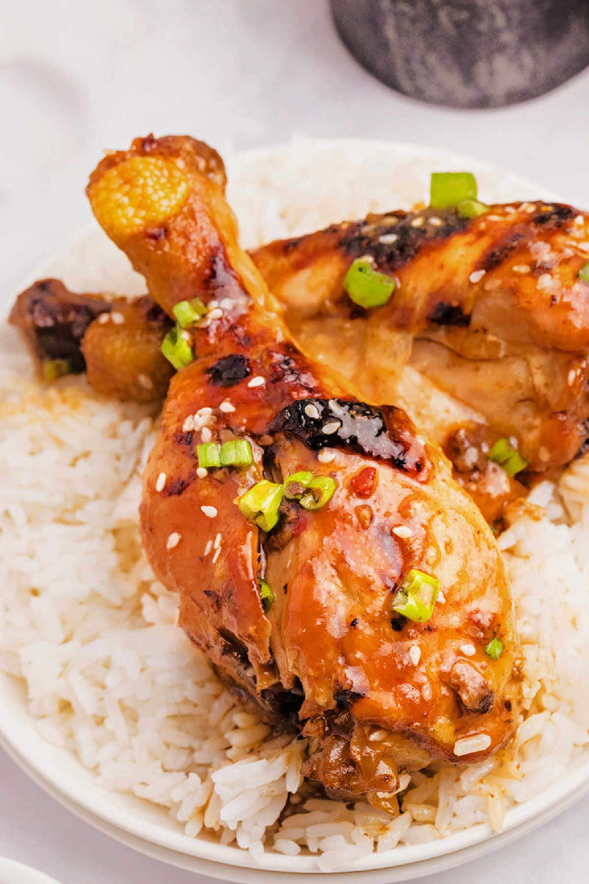 Slow cooker chicken legs piled on a bed of rice on a plate.