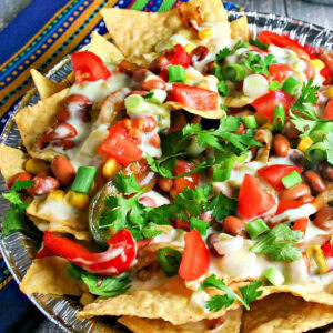 Veggie Nachoes loaded with cheese, bell peppers, beans, corn, onions, tomatoes, and cilantro.