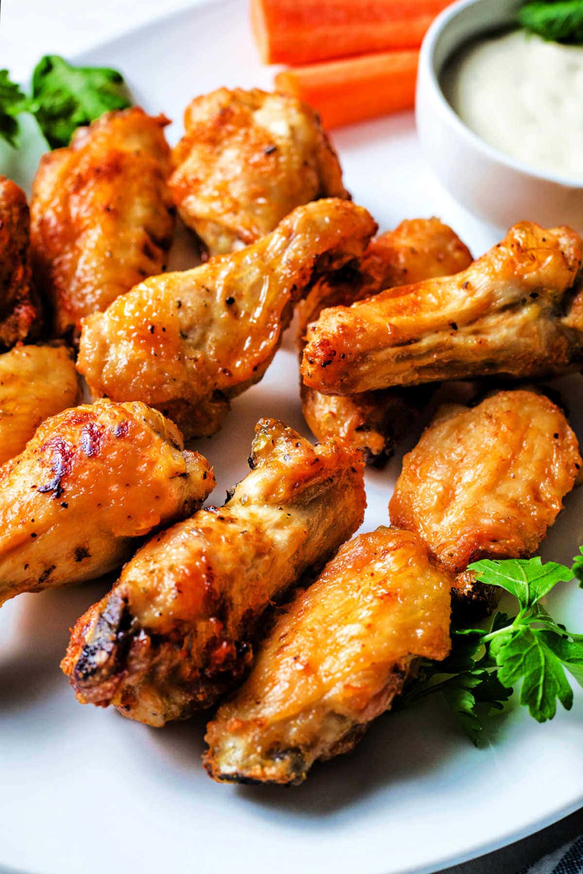 Air fryer chicken wings served on a platter with dip in the background.