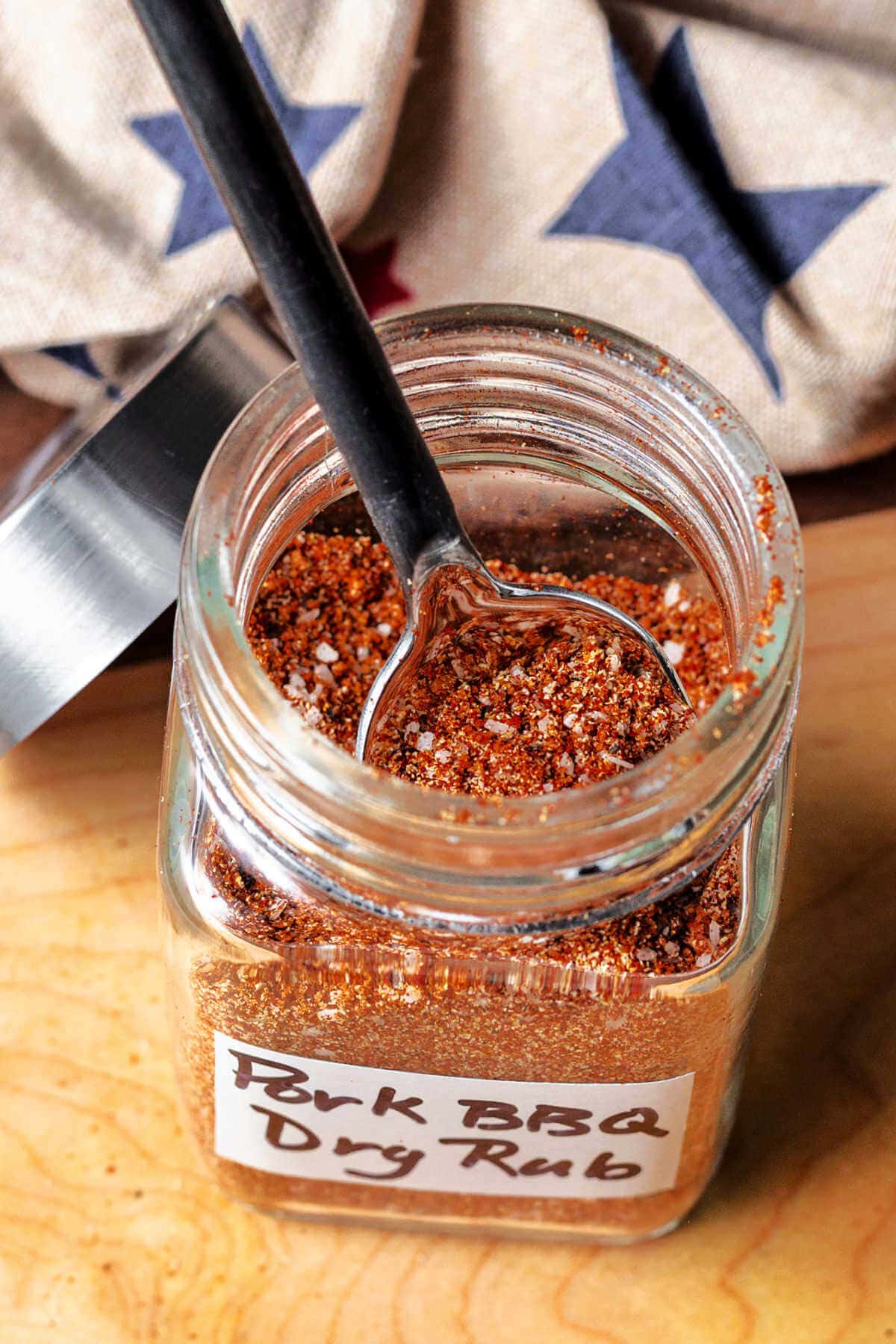 Pulled pork dry rub spices in a spice jar with a small spoon.