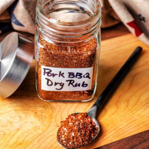 A mixture of spices for pulled pork spice rub in a glass jar.