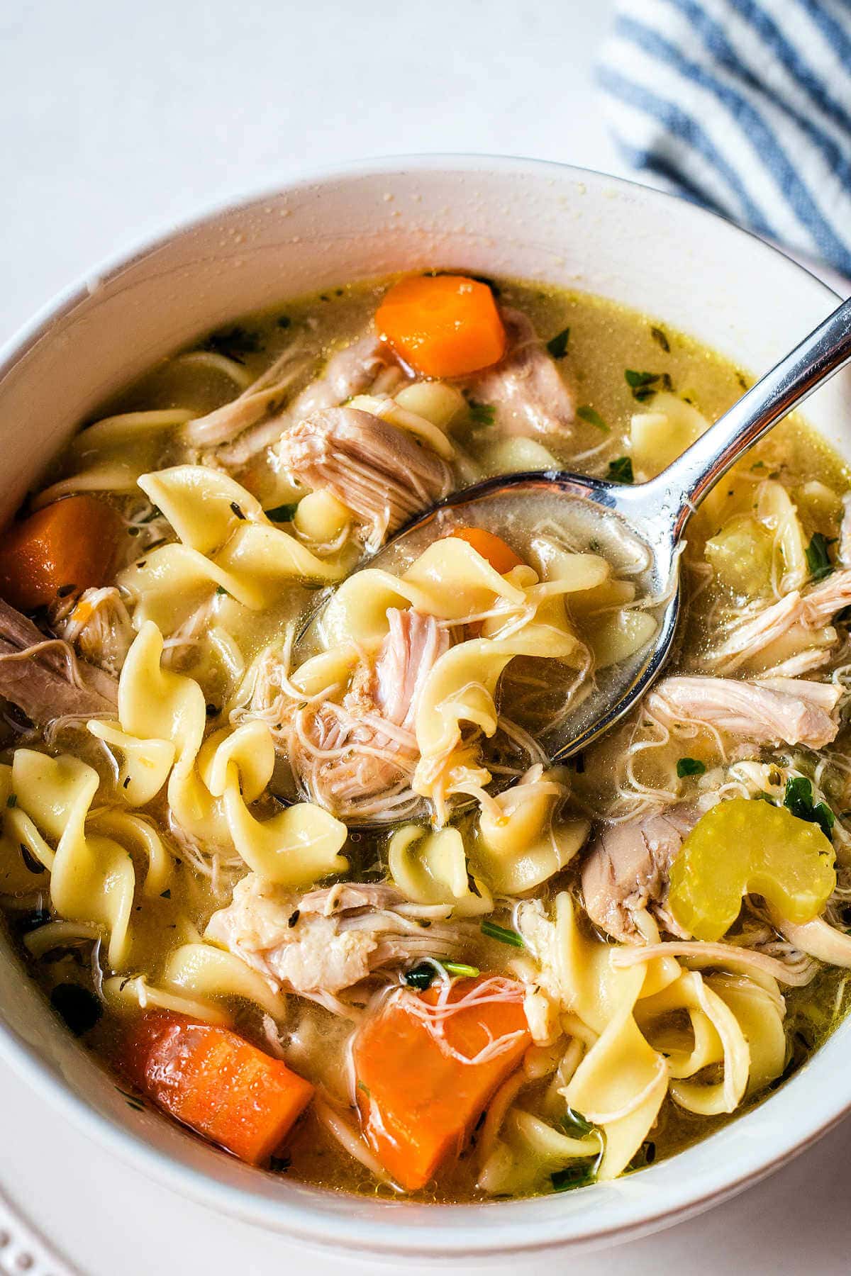 Bowl of Instant Pot chicken noodle soup with a spoon scooping some up.