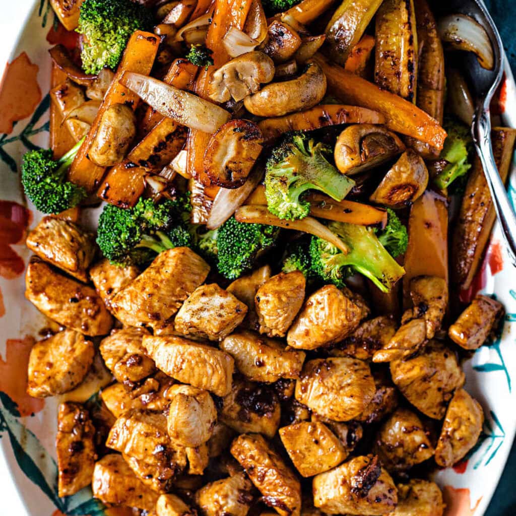 Close up shot of hibachi chicken and vegetables on a platter with a serving spoon on the side.