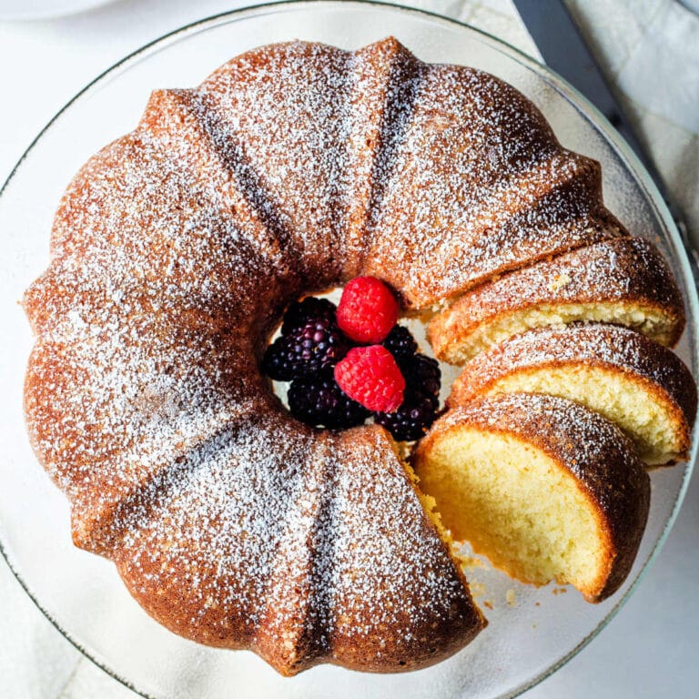 Classic Vanilla Pound Cake on a cake plate with berries.
